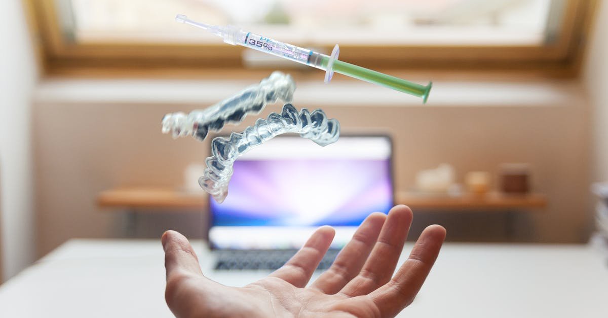 A syringe and dental aligner float above a hand in a modern office, signifying advanced dental care technology.